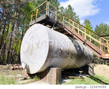 Horizontal tank oil white Storage Fuel Gas Container Tanks. horizontal steel tank. large metal barrel with a ladder in the forest area Horizontal tank oil white Storage Fuel Gas Container Tanks. horizontal steel tank. large metal barrel with a ladder in the forest area 125874393