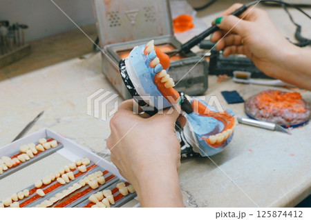 Expert technician crafts custom dentures with precision and care Expert technician crafts custom dentures with precision and care 125874412