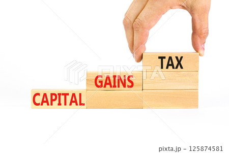 Capital gains tax symbol. Concept words Capital gains tax on beautiful wooden block. Businessman's hand. Beautiful white background. Business and capital gains tax concept. Copy space. 125874581