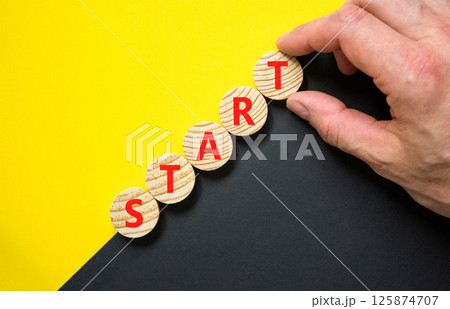 Start symbol. Concept word Start on beautiful wooden circles. Beautiful yellow and black background. Businessman hand. Business lifestyle start concept. Copy space. 125874707