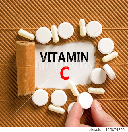 Vitamin C symbol. Concept words Vitamin C on beautiful white paper. White pills tablets. Doctor's hand. Beautiful brown background. Medical healthy lifestyle Vitamin C concept. 125874763