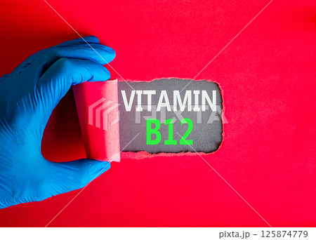 Vitamin B12 symbol. Concept words Vitamin B12 on beautiful grey paper. Doctor hand in blue medical glove. Beautiful red background. Medical healthy lifestyle Vitamin B12 concept. Vitamin B12 symbol. Concept words Vitamin B12 on beautiful grey paper. Doctor hand in blue medical glove. Beautiful red background. Medical healthy lifestyle Vitamin B12 concept. 125874779