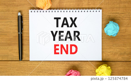 Tax year end symbol. Concept words Tax year end on beautiful white note. Beautiful wooden background. Black pen. Colored paper. Business tax year end concept. Copy space. Tax year end symbol. Concept words Tax year end on beautiful white note. Beautiful wooden background. Black pen. Colored paper. Business tax year end concept. Copy space. 125874784