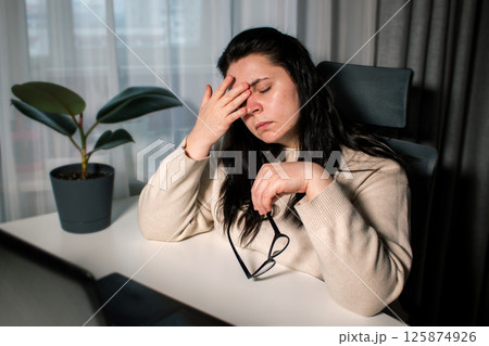 Woman working from home office sitting with laptop rubbing tired eyes. Burnout, stress, fatigue at work concept Woman working from home office sitting with laptop rubbing tired eyes. Burnout, stress, fatigue at work concept 125874926