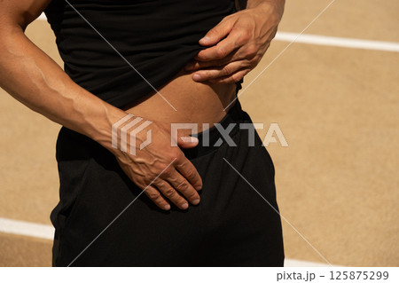 Man holds his abdomen in pain, highlighting discomfort or potential injury during exercise. Health care concept 125875299