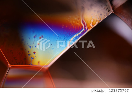 Bright rainbow reflection of liquid on black background, red colours, surrealistic pattern 125875797