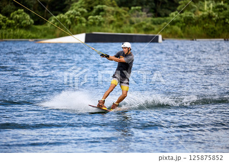 Wakeboarder Riding on Water Holding Tow Rope Wakeboarder Riding on Water Holding Tow Rope 125875852