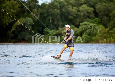 Wakeboarder Riding on Water Holding Tow Rope Wakeboarder Riding on Water Holding Tow Rope 125875855