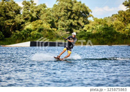 Wakeboarder Riding on Water Holding Tow Rope 125875863