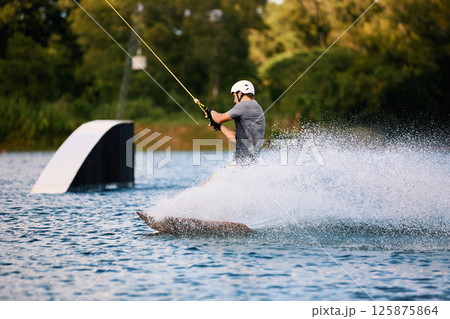 Wakeboarder Riding on Water Holding Tow Rope Wakeboarder Riding on Water Holding Tow Rope 125875864