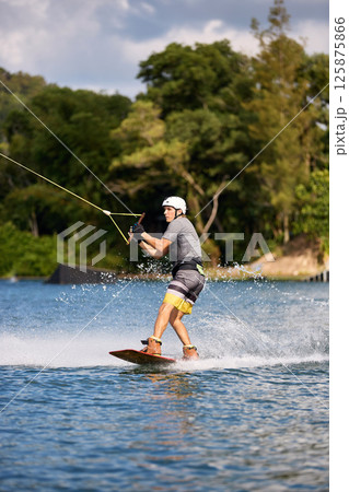 Wakeboarder Riding on Water Holding Tow Rope 125875866