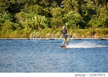 Wakeboarder Riding on Water Holding Tow Rope Wakeboarder Riding on Water Holding Tow Rope 125875871