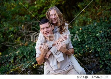 Young Cute Female Hugs Boyfriend. In Autumn Outdoor. Lovers Walking in Park. Attractive Funny Couple. Lovestory in Forest. Man and Woman. Cute Lovers in the Park. Family Concept. Happy Couple. 125876026