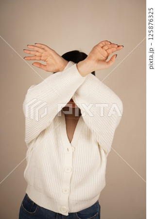 Her posture conveys a sense of defense and strength. The gesture shows determination and resolve. A woman crosses her arms in front of her, fists clenched, signaling readiness for protection. 125876325