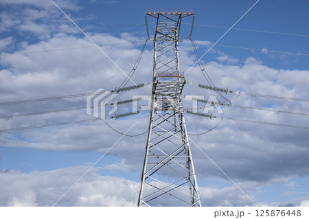Tower of a high-voltage power line against the of blue sky and clouds 125876448