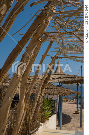 Traditional straw beach umbrella on the beach, with a sunny day on the Mediterranean coast 125876644