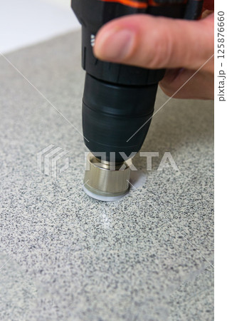 rotating diamond core drill bit starts drilling into a stone slab 125876660