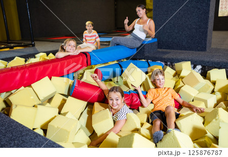 Tween children having fun in pool with foam cubes 125876787