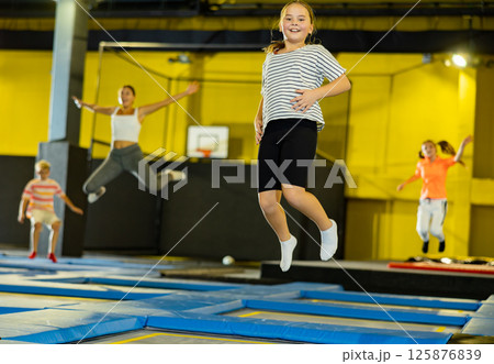 Tween girl having fun jumping in indoor trampoline arena 125876839