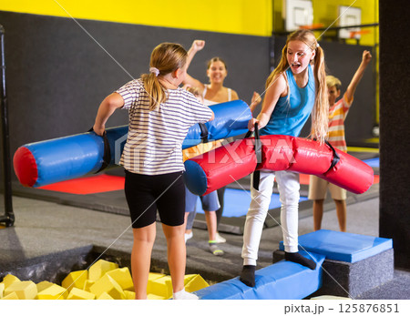 Team of friends playing with inflatable sticks in amusement park 125876851