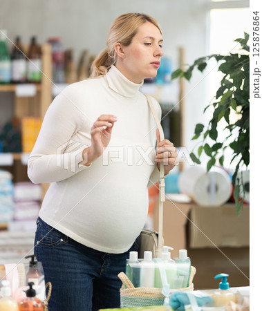 Interested pregnant woman choosing home care products in store Interested pregnant woman choosing home care products in store 125876864