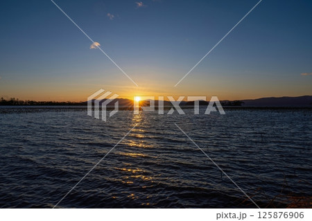 琵琶湖の山並みに沈む夕日の光条と夕焼けのコラボ情景 琵琶湖の山並みに沈む夕日の光条と夕焼けのコラボ情景 125876906