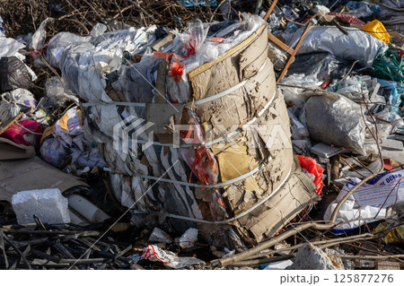 Trash and recyclable materials are seen stacked at a waste management site during daylight, highlighting urban waste challenges Trash and recyclable materials are seen stacked at a waste management site during daylight, highlighting urban waste challenges 125877276