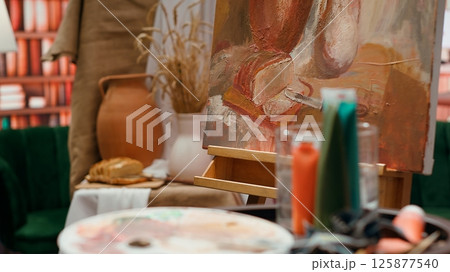 Empty art and craft workshop with a rustic beautiful painting on canvas, creative work with watercolor paint in a modern contemporary atelier. Artistic masterpiece with paint tubes and tools. Empty art and craft workshop with a rustic beautiful painting on canvas, creative work with watercolor paint in a modern contemporary atelier. Artistic masterpiece with paint tubes and tools. 125877540