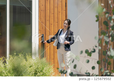 玄関を出るスーツ姿の女性 125879502