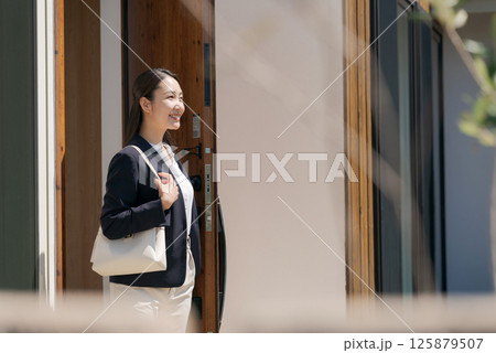 玄関を出るスーツ姿の女性 125879507
