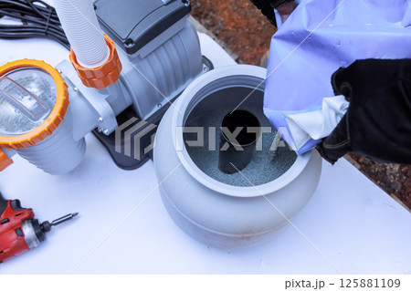 Assembling components of pool filtration system on works day in backyard setting, near swimming pool 125881109