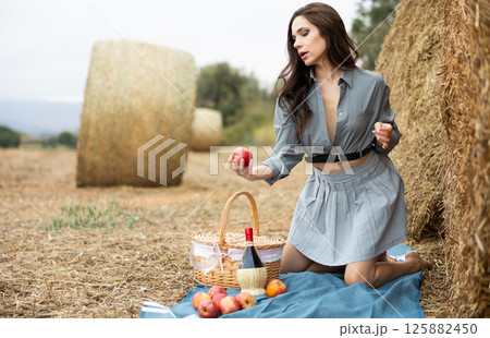Female brunette with long hair wearied in grey suit poses near haystack. 125882450