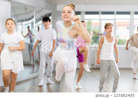 Team of teenagers rehearsing modern dances in dance hall Team of teenagers rehearsing modern dances in dance hall 125882485
