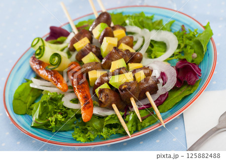 Tasty shish kebab from chicken hearts with avocado and lettuce at plate 125882488