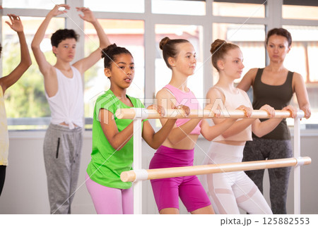 Woman teacher corrects teenagers in plie movement 125882553