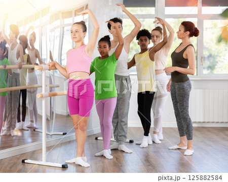 Teen girl learning third ballet position in beginner class Teen girl learning third ballet position in beginner class 125882584