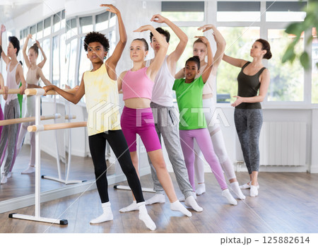 Teenage boys and girls practicing battement tendu position of ballet in dancehall 125882614