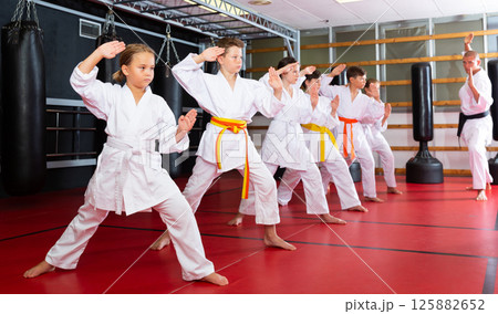 Children wearing karate uniform practicing new moves in group Children wearing karate uniform practicing new moves in group 125882652