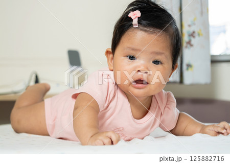 Newborn asian baby crawling in cozy indoor space - adorable lifestyle moment 125882716