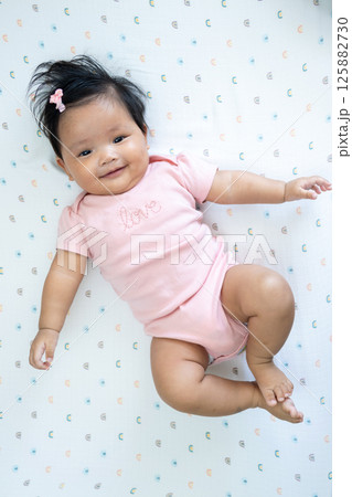 Joyful newborn asian baby smiling cozy indoor setting high-quality playful atmosphere 125882730