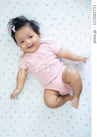 Happy newborn baby girl asian heritage indoor portrait playful environment close-up view 125882731