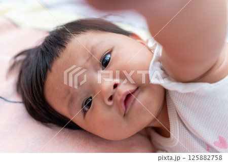 Newborn asian baby exploring her world cozy home candid image indoor close-up moment 125882758