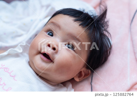 Joyful newborn asian baby portrait home cozy close-up happiness 125882764