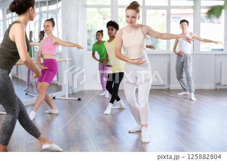 Teenage girl practicing basic ballet moves at group class 125882804