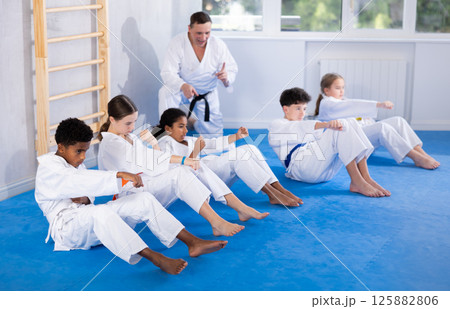 Teenagers performing core twist with punches during martial arts training Teenagers performing core twist with punches during martial arts training 125882806