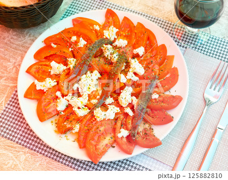 Tasty tomato slices with cheese and anchovies. 125882810