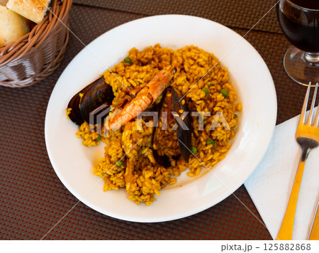 Spanish rice dish paella tinted with saffron. Prepared with olive oil and seafood Spanish rice dish paella tinted with saffron. Prepared with olive oil and seafood 125882868