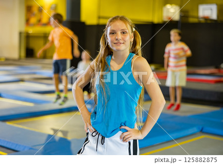 Cheerful teen girl standing on trampoline on indoor inflatable playground Cheerful teen girl standing on trampoline on indoor inflatable playground 125882875