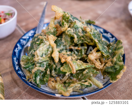 Crispy fried greens delight local market food urban setting close-up culinary experience Crispy fried greens delight local market food urban setting close-up culinary experience 125883101