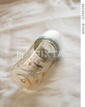 Feeding time for babies transparent baby bottle soft surface lifestyle setting close-up viewpoint 125883260